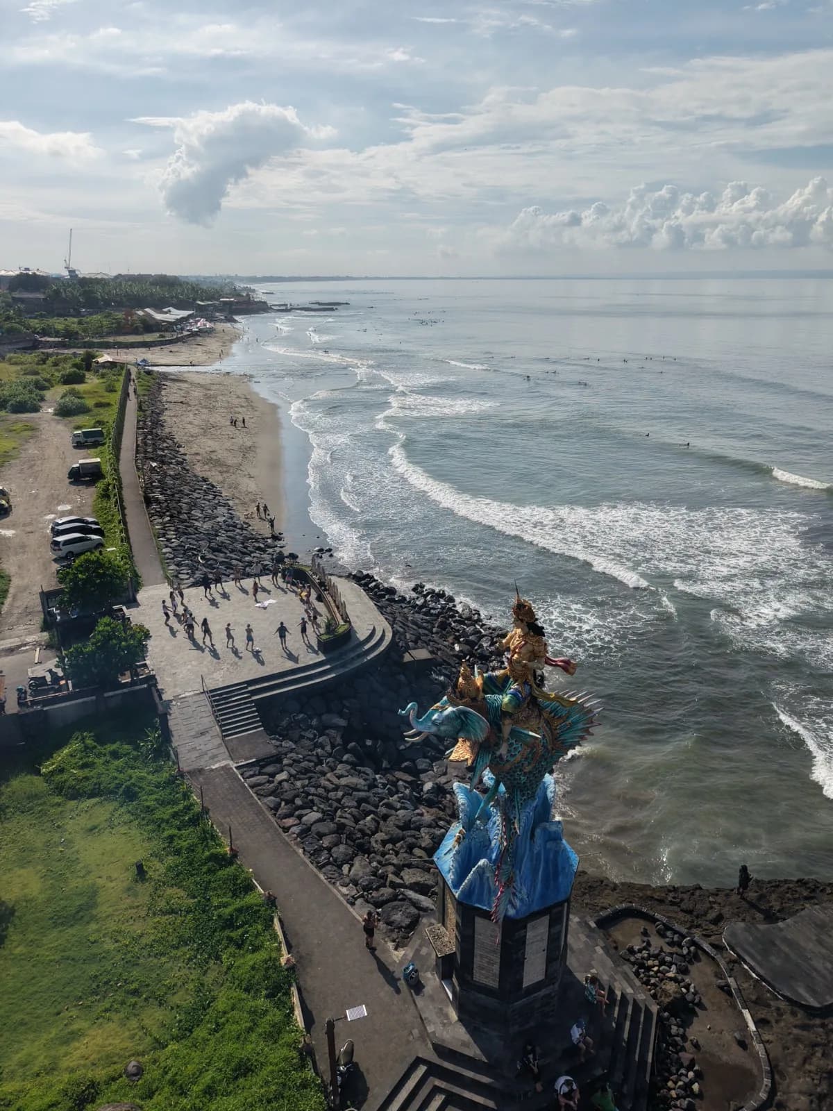 Surfers, statue, and a clean stretch of coast